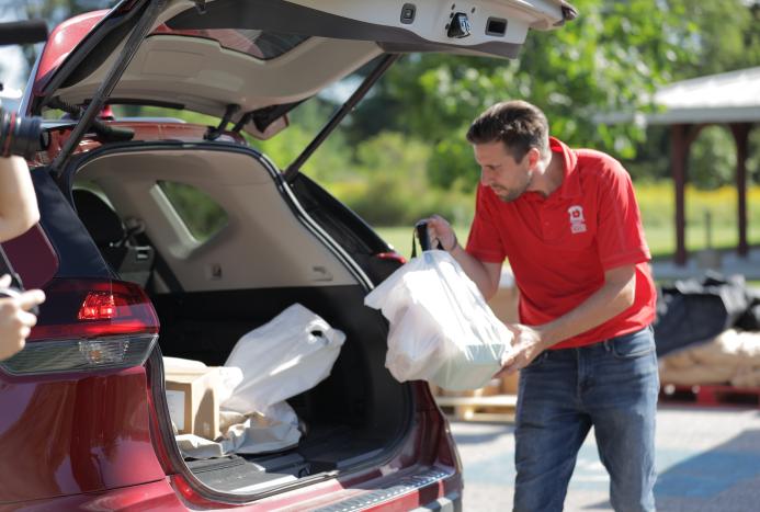 Car being loaded with food by volunteer