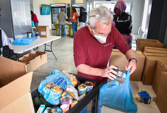 volunteers and staff members are stocking the shelves of the Keith D. Monda Family Food Pantry