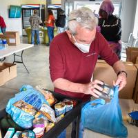 volunteers and staff members are stocking the shelves of the Keith D. Monda Family Food Pantry